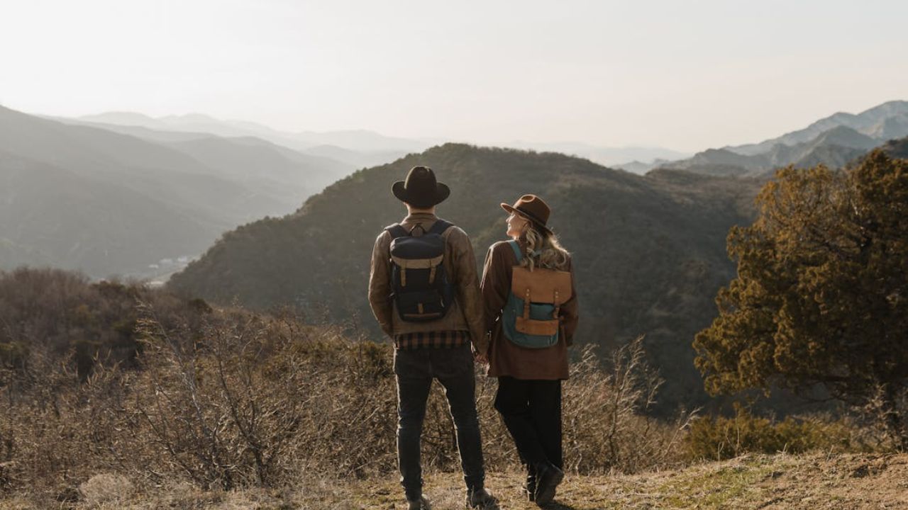 Couple with backpacks holding hands and looking at a mountain view