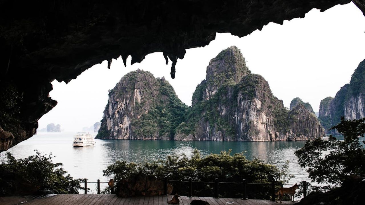 View of limestone karsts and a boat on the water, seen from inside a cave at Ha Long Bay, Vietnam.