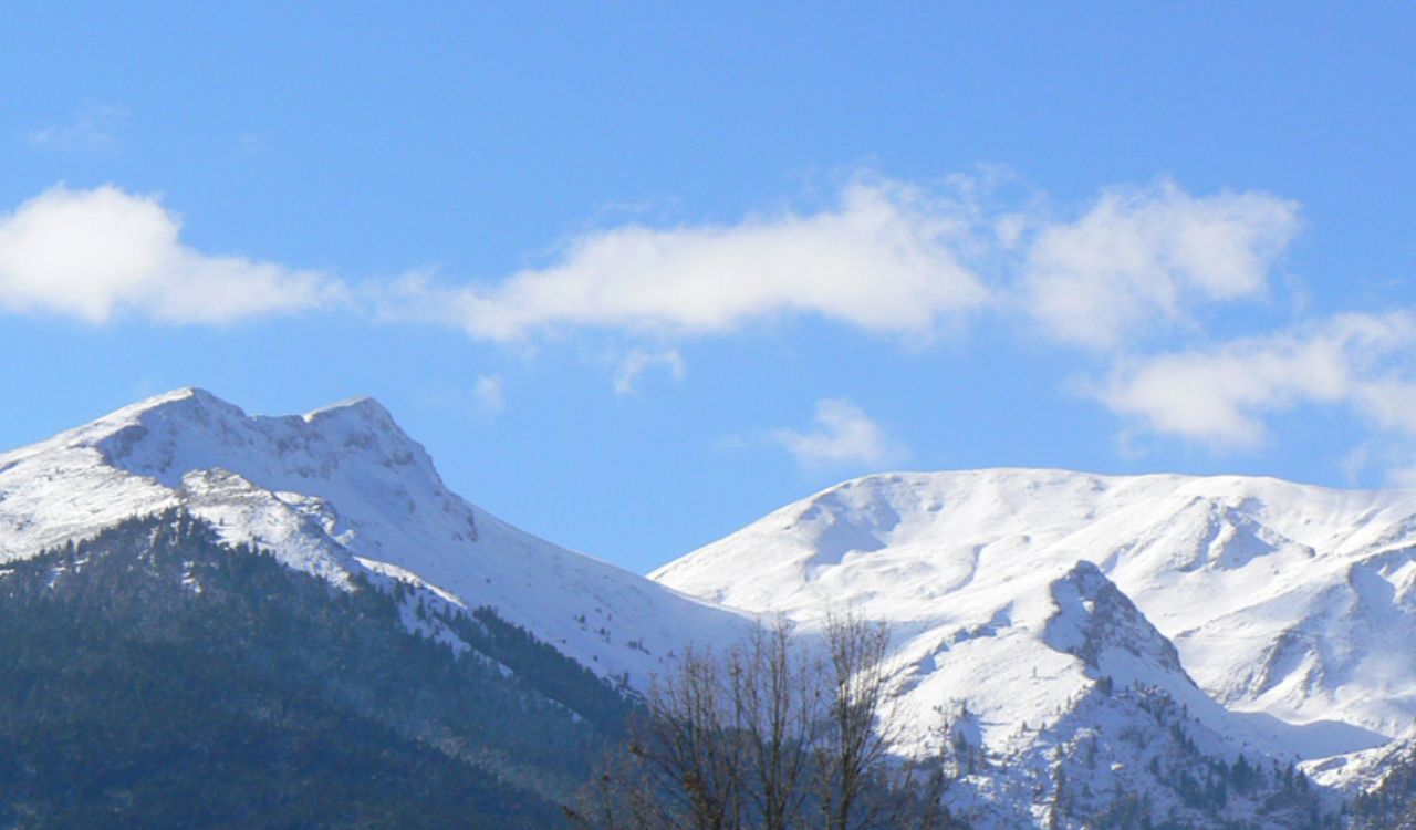 Snow-covered Pindus peaks in Agrafa, Greece, against a clear blue sky