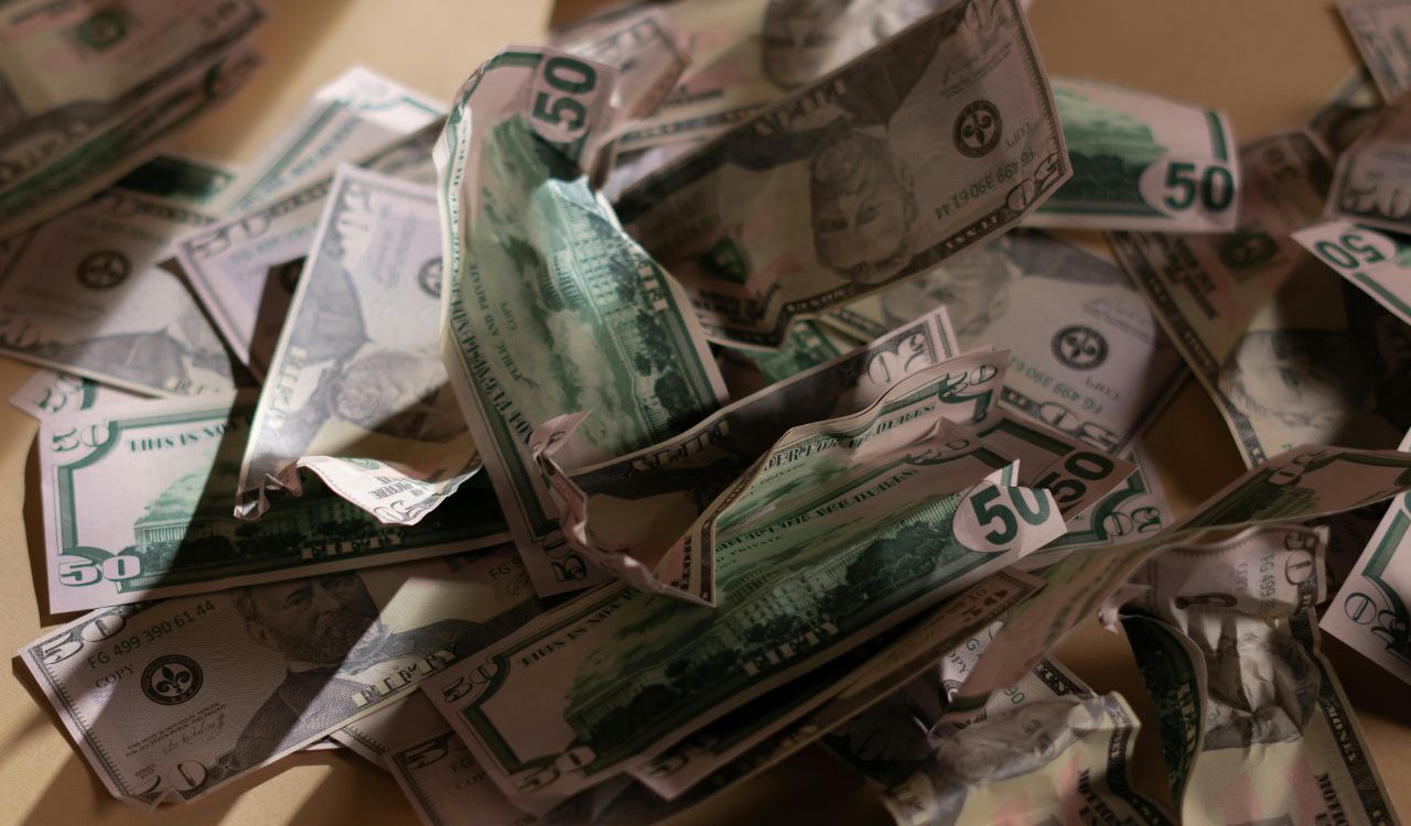 Crumpled U.S. fifty-dollar bills scattered on a surface.