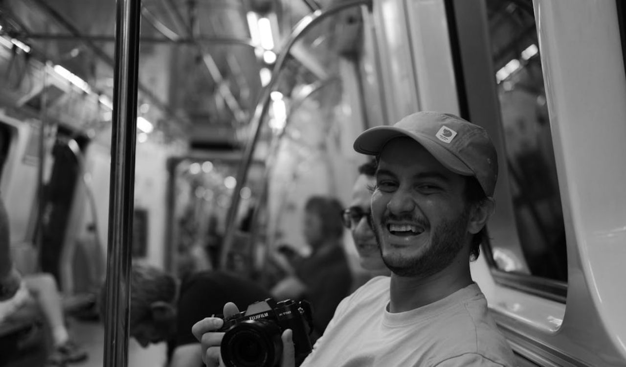 Smiling man holding a camera on a train