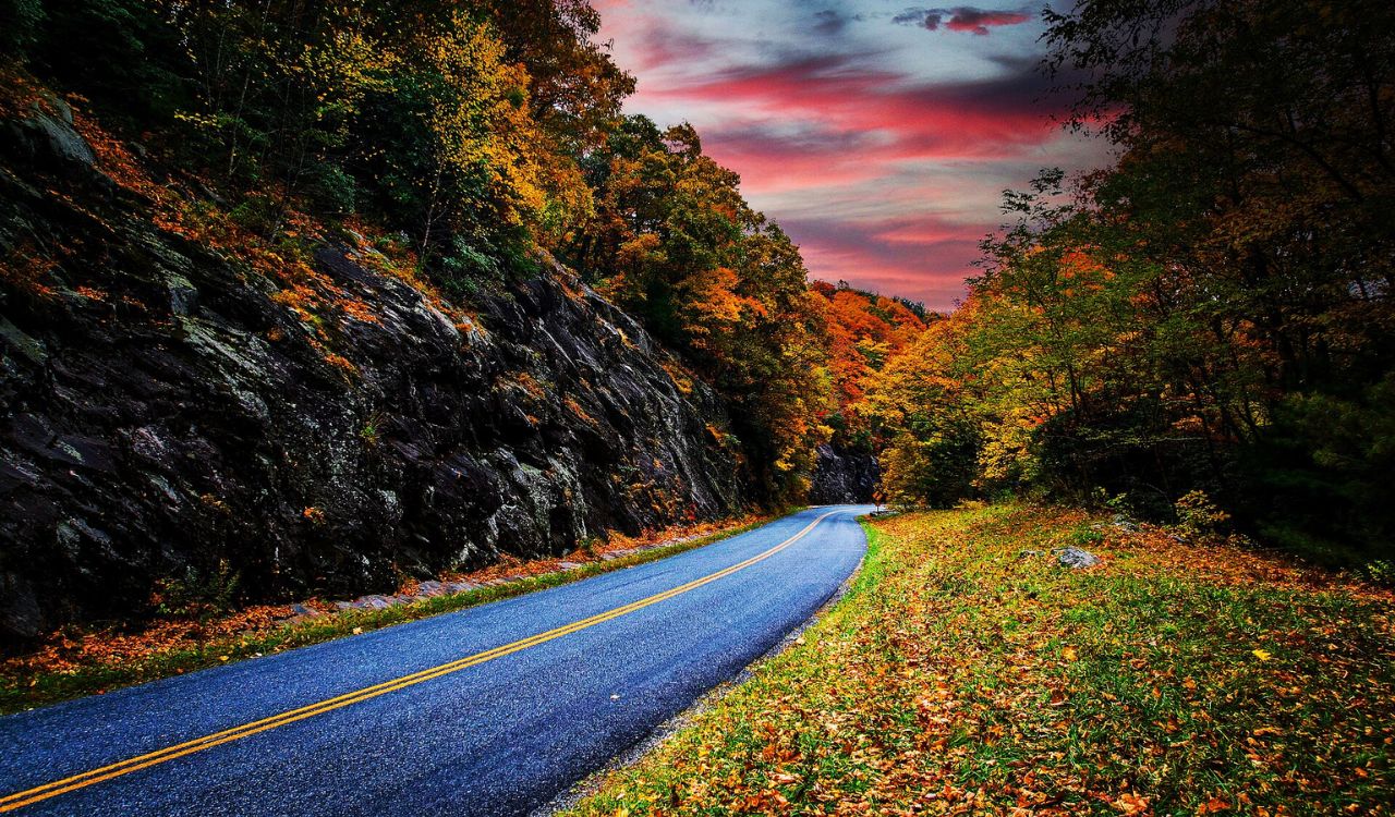 Blue Ridge Parkway winds through glowing autumn trees under a colorful sky