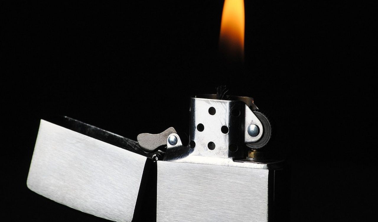 Close-up image of an open silver Zippo lighter with a flame burning