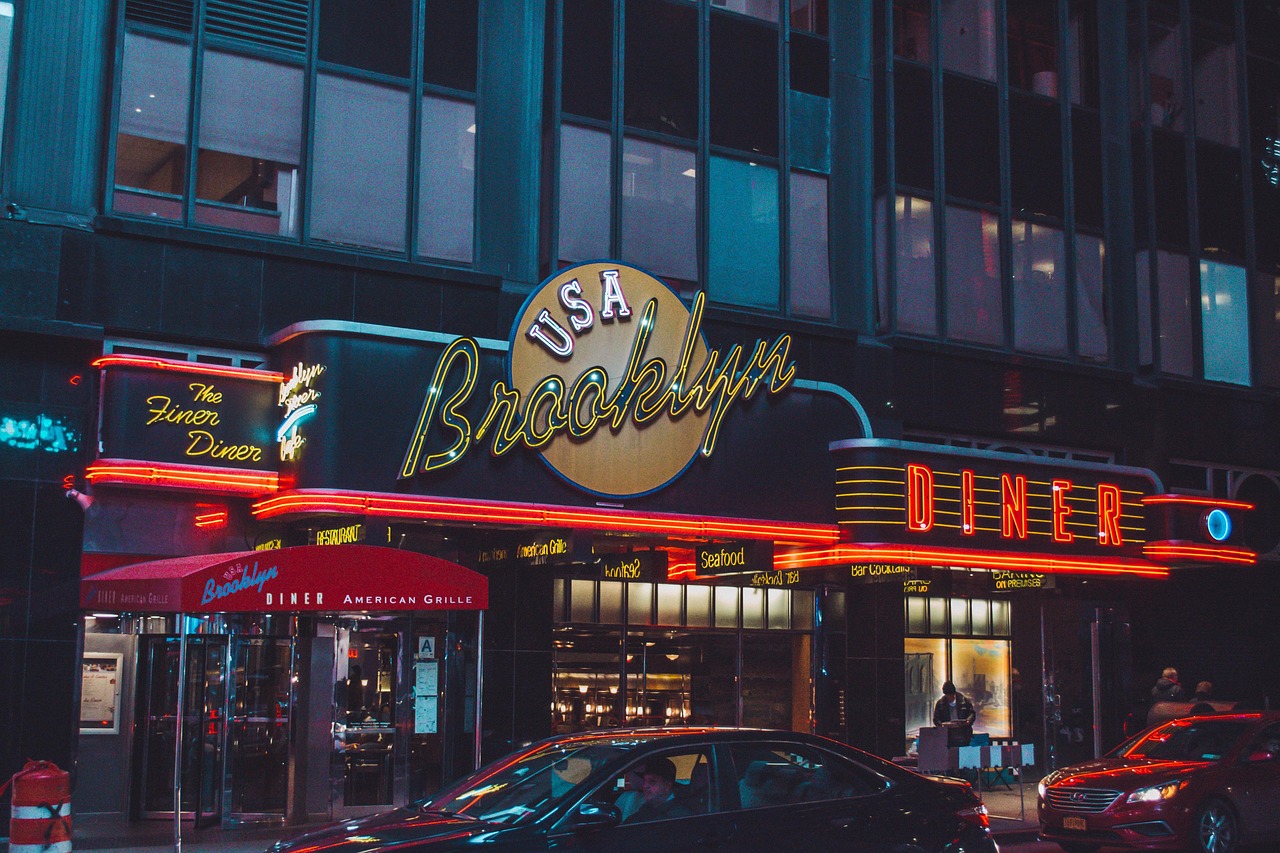 The neon-lit "USA Brooklyn Diner" exterior features parked cars and people near the entrance.