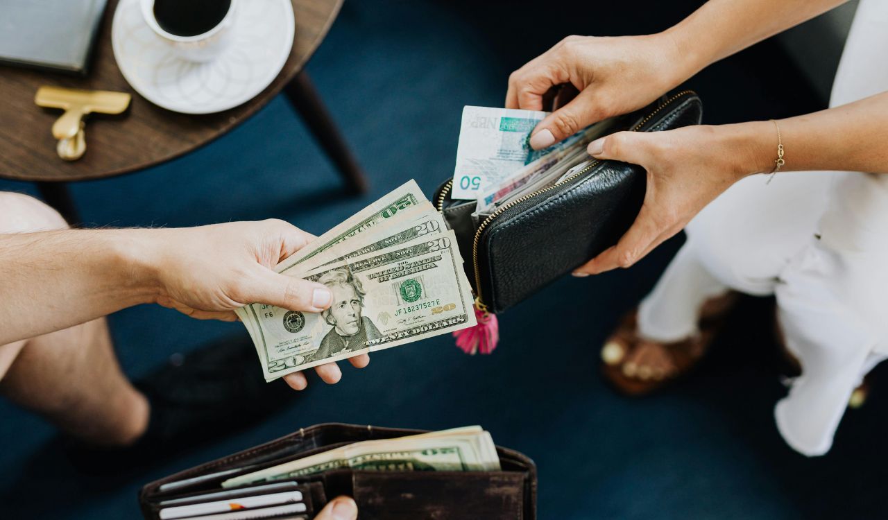 Hands holding and organizing cash into separate wallets.