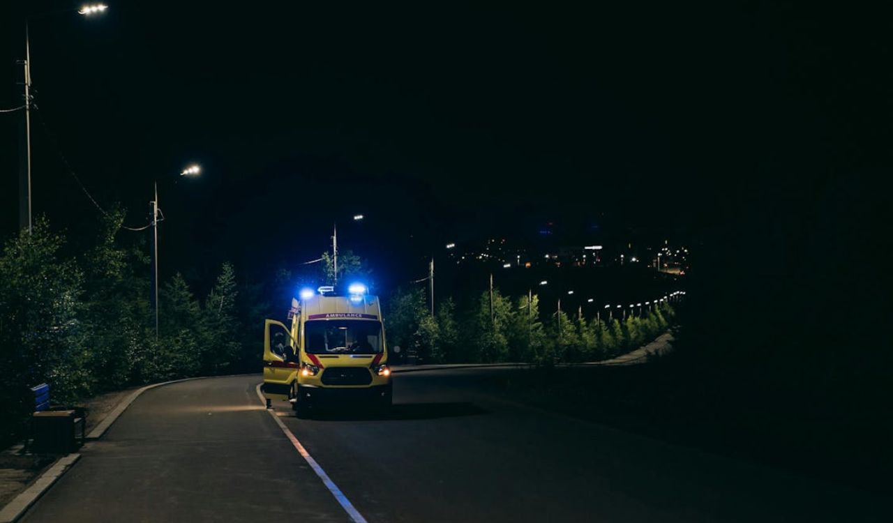 Ambulance with flashing lights parked on a dark road at night