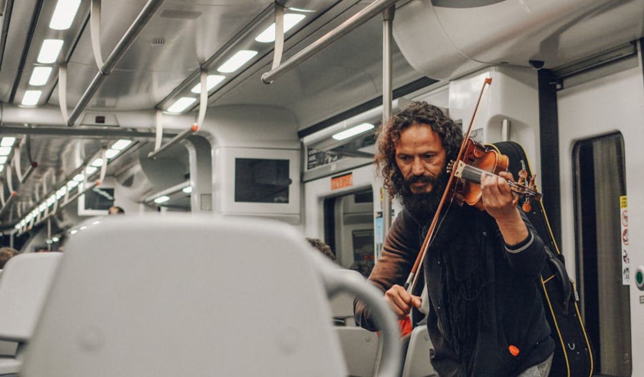 Street musician playing violin for passengers on a modern train carriage