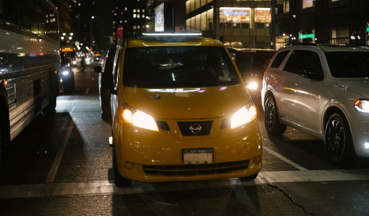 Yellow taxi driving through city traffic at night