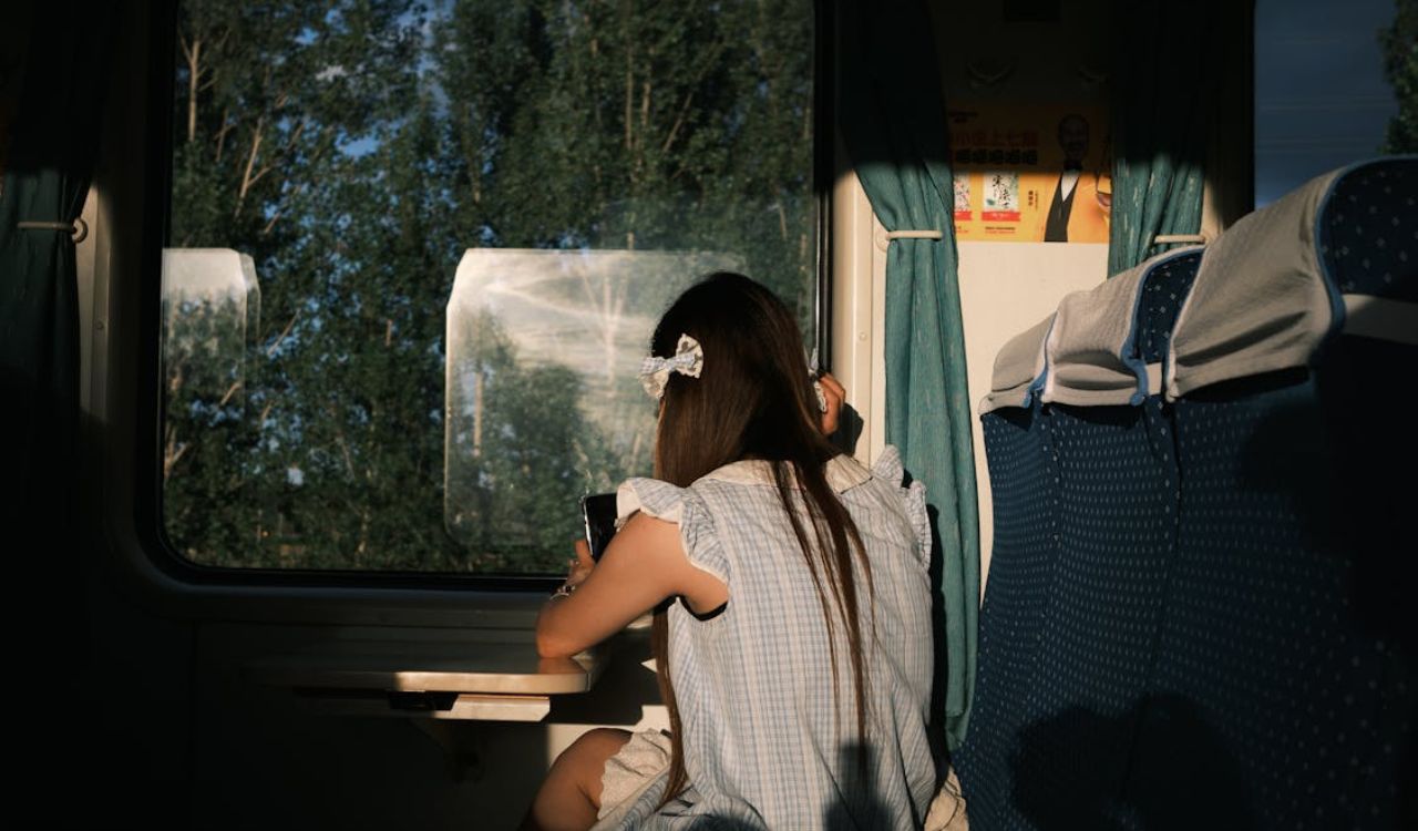 Young woman enjoying scenic train ride while wearing a comfortable dress