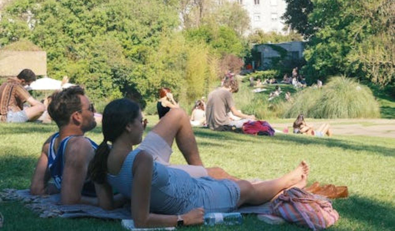 Couple relaxing on a grassy field in a lively public park on a sunny day