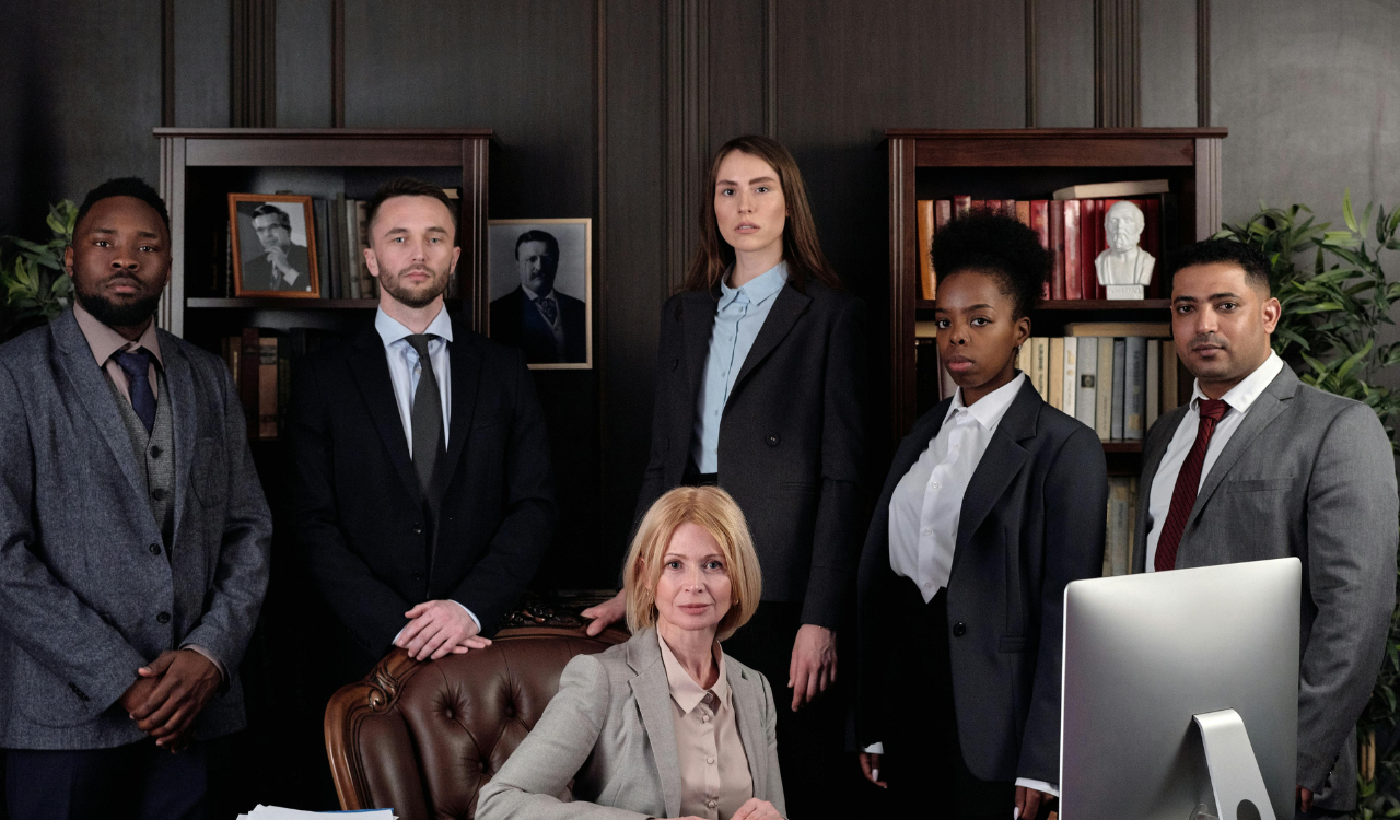A diverse business team poses in a formal office setting.