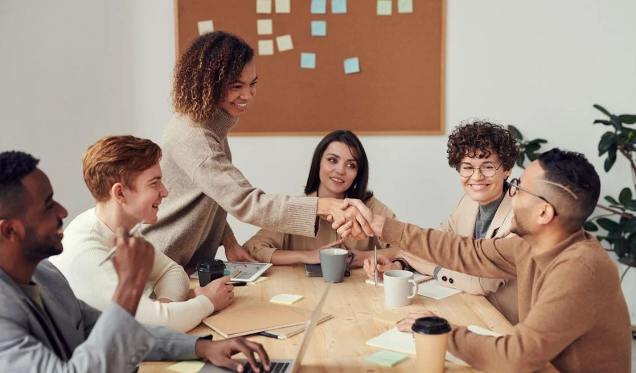 Colleagues smile and shake hands in a warm meeting