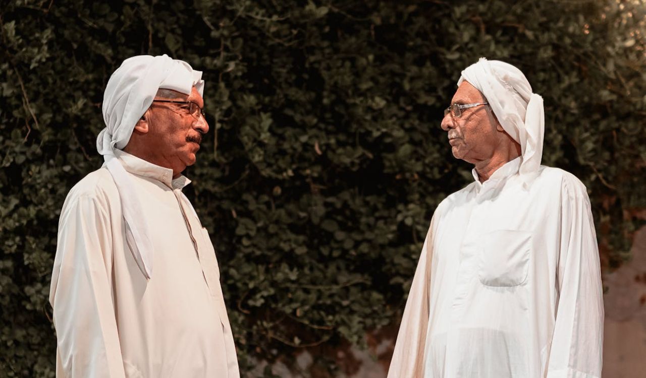 Two elderly men in traditional attire engaged in a respectful conversation