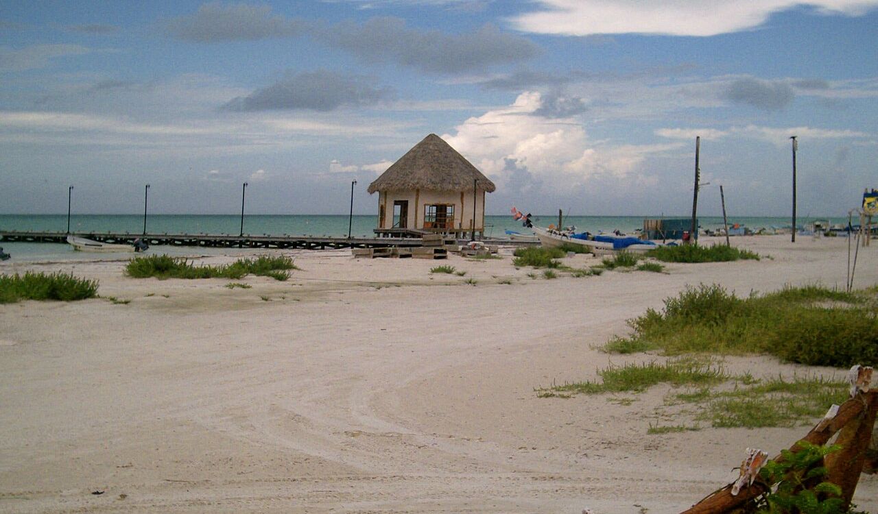 Quiet sandy beach with a thatched hut and calm turquoise waters in Isla Holbox