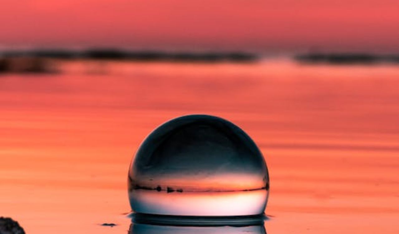 Crystal ball reflecting vivid sunset over tranquil seaside rocks