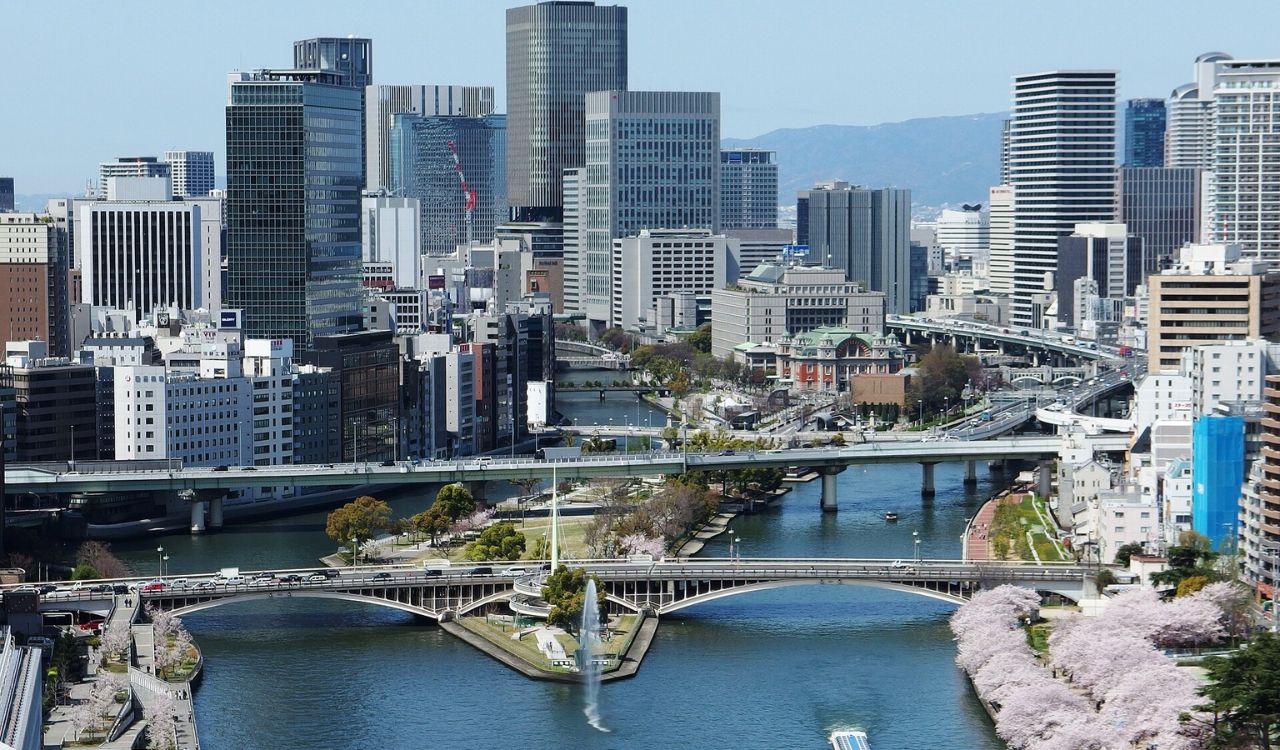 Modern skyline of Osaka, Japan with cherry blossoms and river bridges in spring