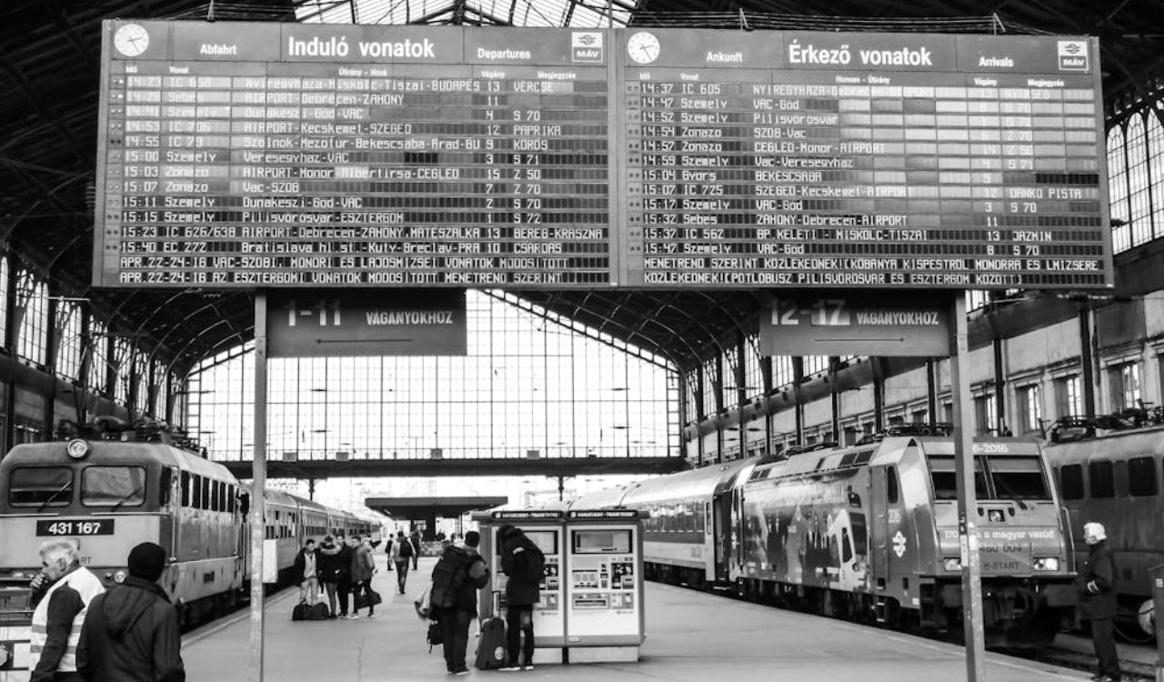 Travelers checking train schedule at Hungarian railway station