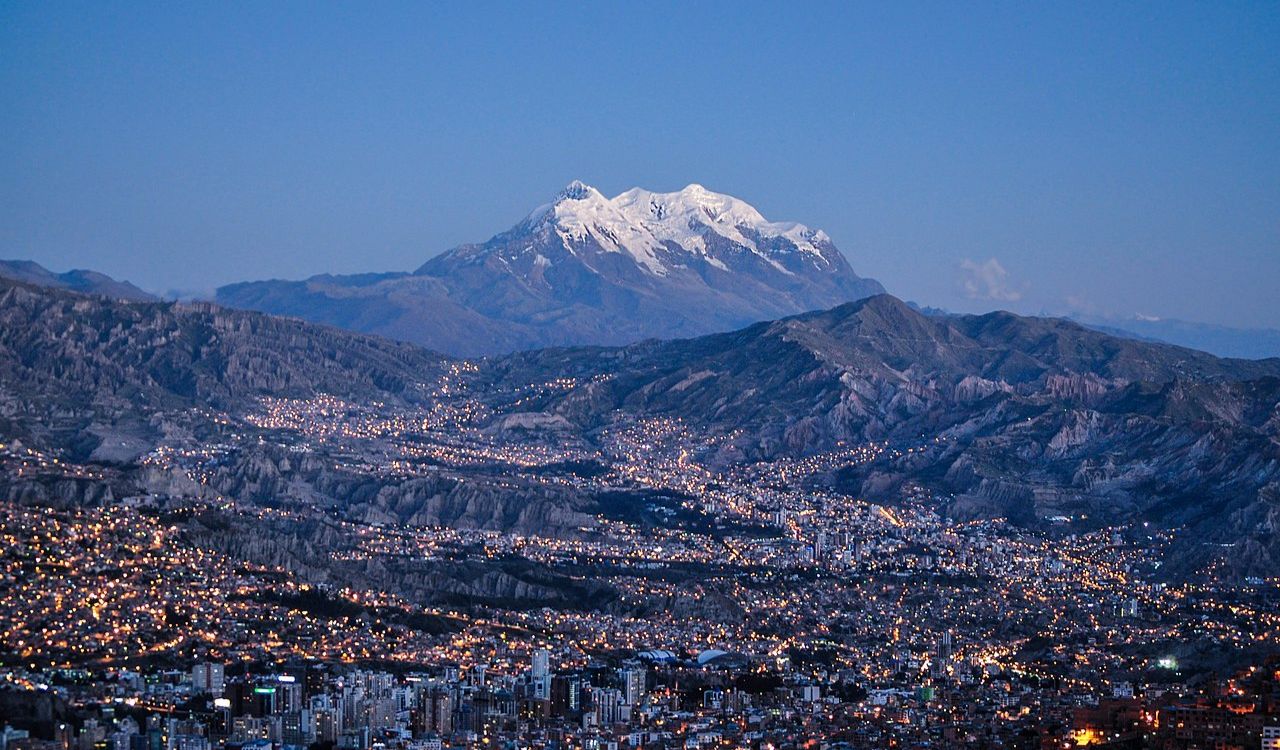 La Paz glows at twilight beneath the towering, snow-capped Mount Illimani