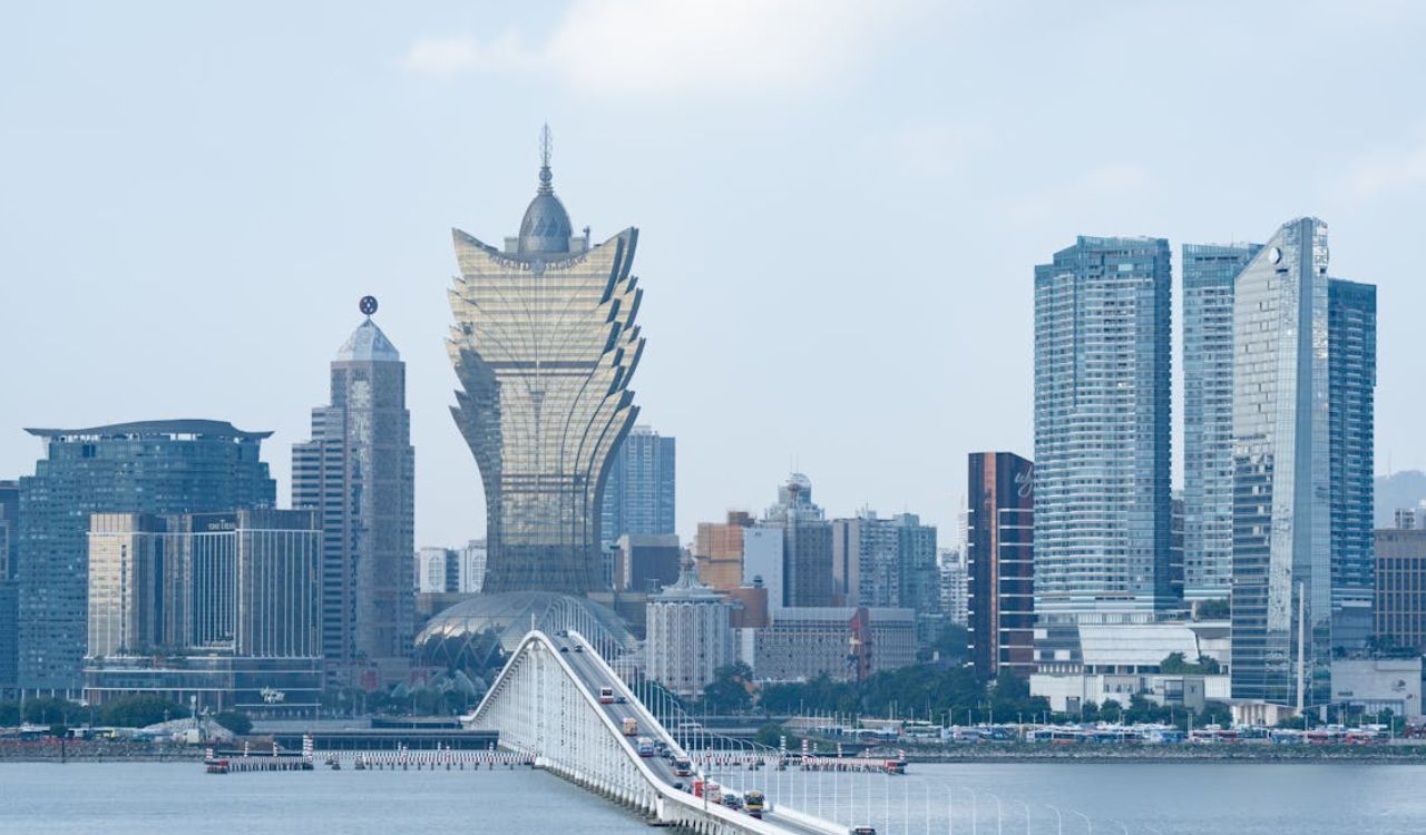 A scenic view of Macau's skyline, featuring the iconic Grand Lisboa Hotel and the modern skyline, with a bridge connecting the cityscape