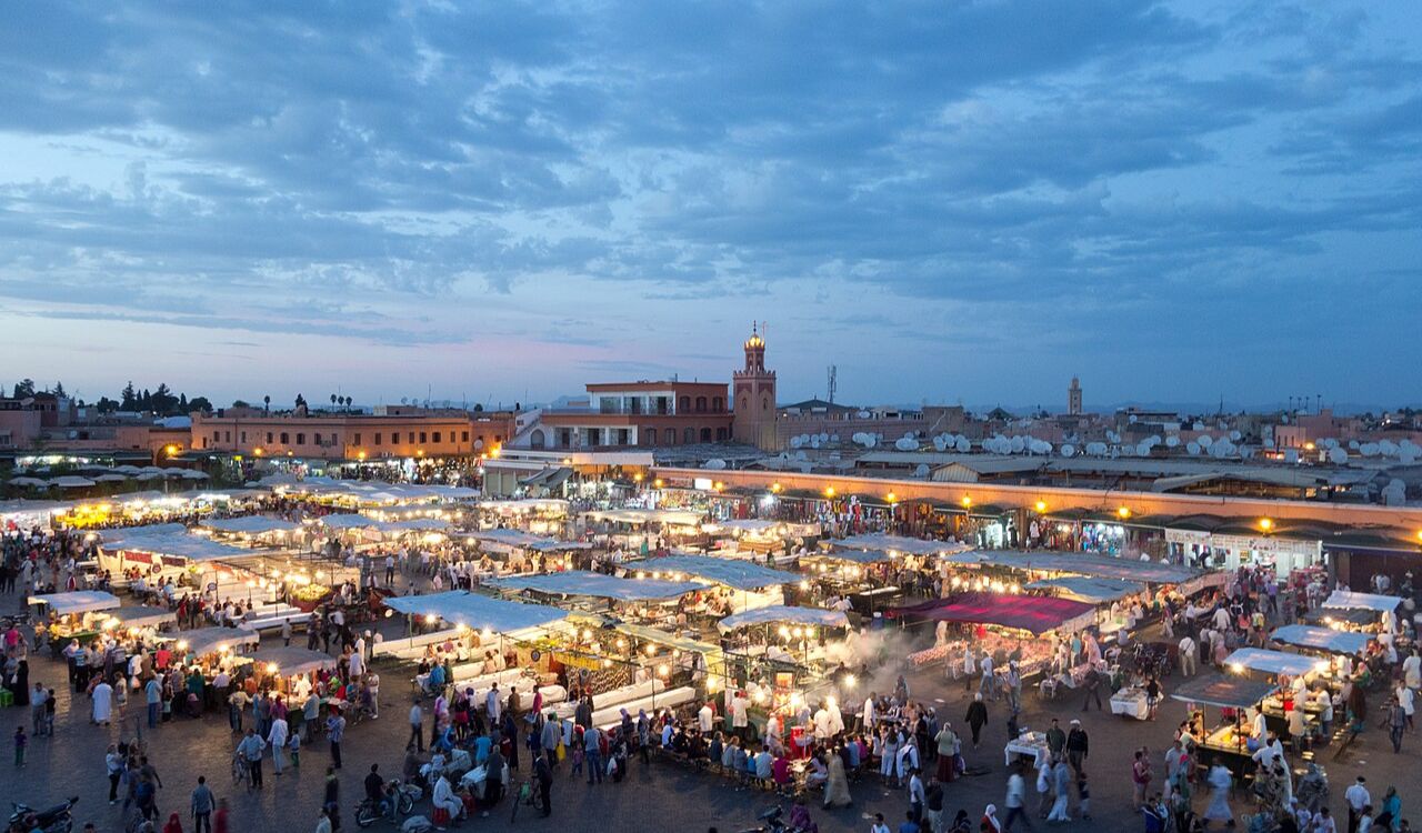 Evening view of a busy market square in Marrakesh with food stalls and crowds