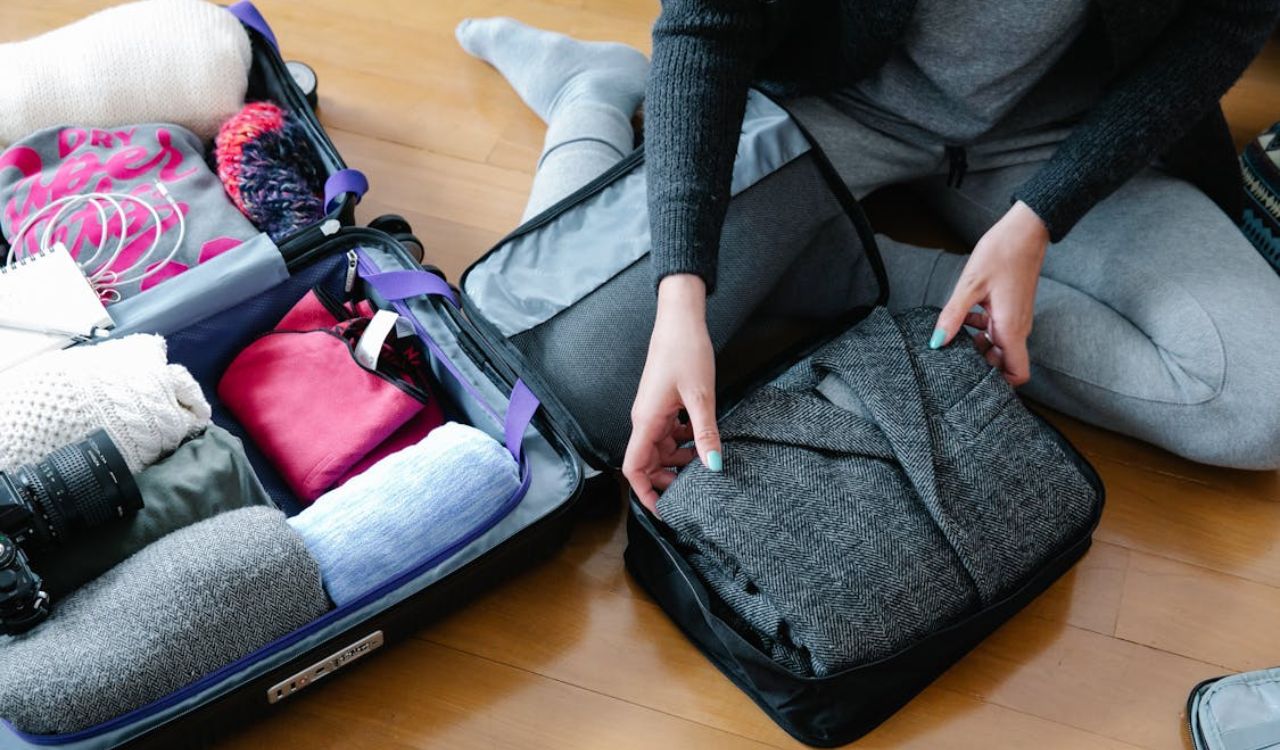 Person packing clothes into a suitcase using packing cube