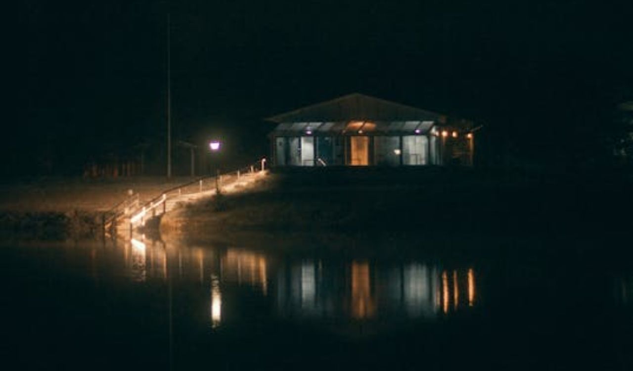Cabin by the lake glowing warmly at night