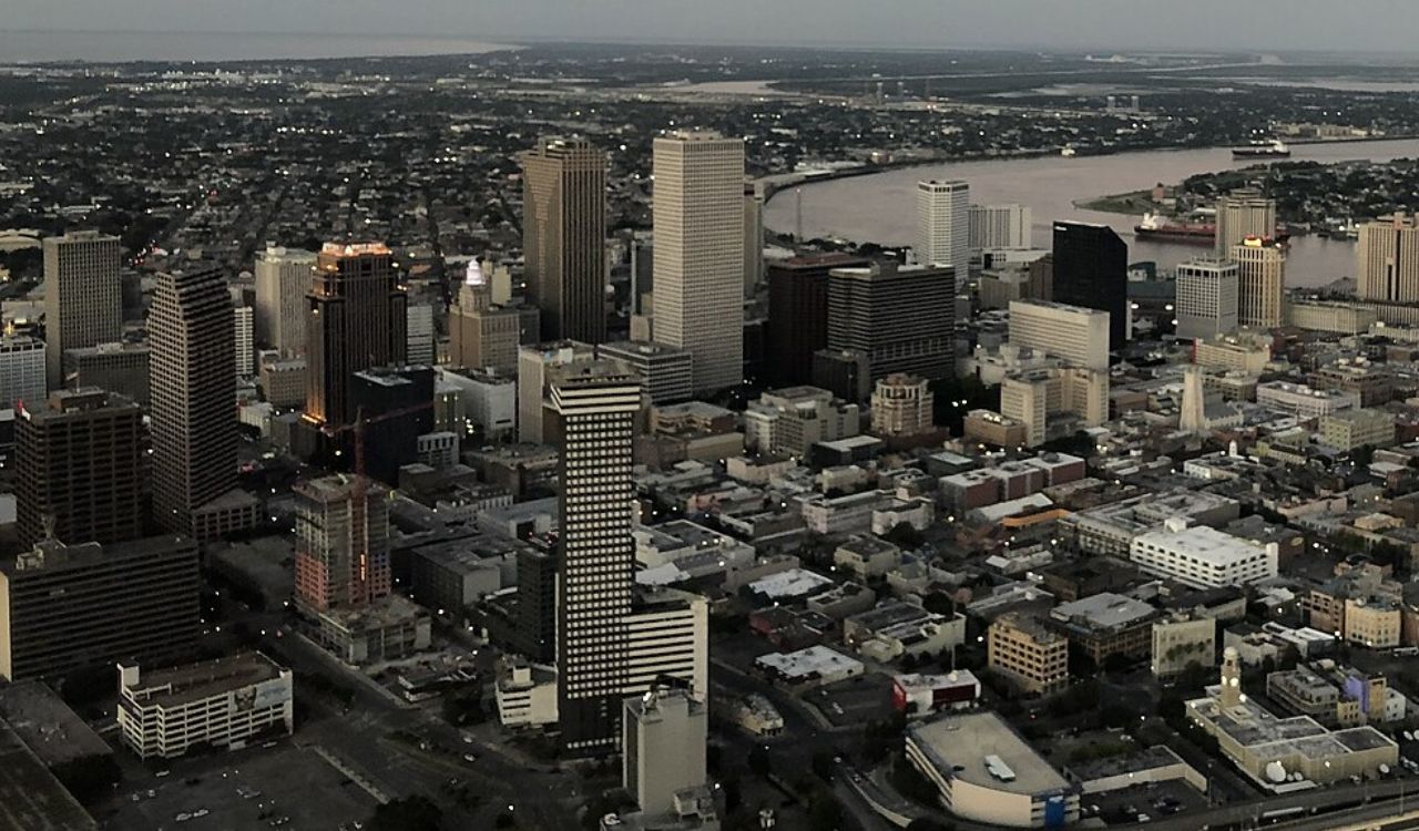 Downtown New Orleans at twilight, with skyscrapers and the Mississippi River.