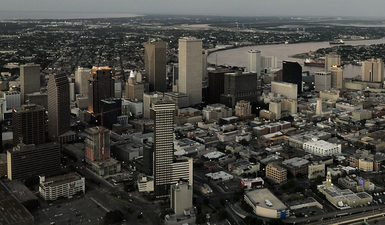 Aerial view of downtown New Orleans skyline at dusk with the Mississippi River in the background