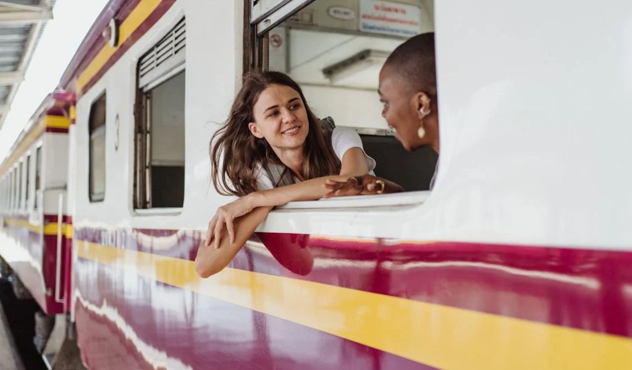 Two women talking at a train window before departure