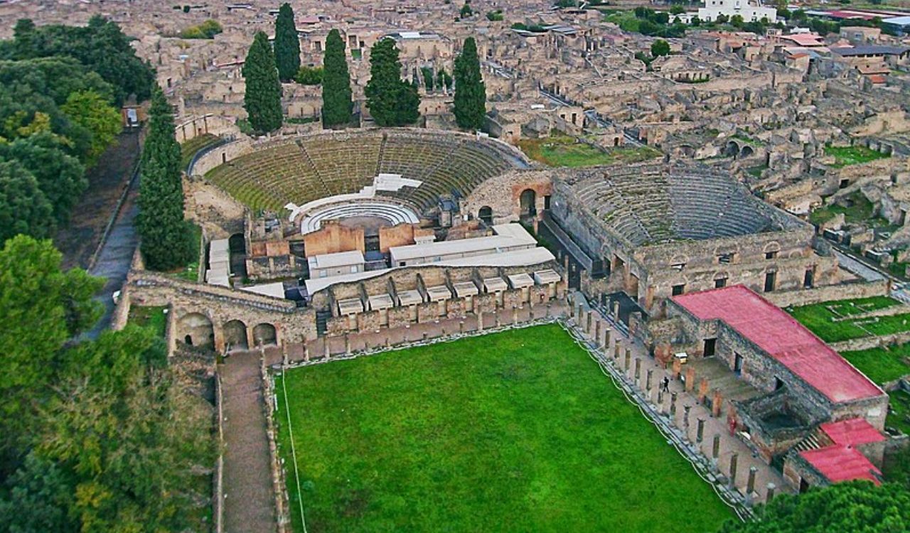 Aerial view of Pompeii ruins with the amphitheater and Mount Vesuvius in the background
