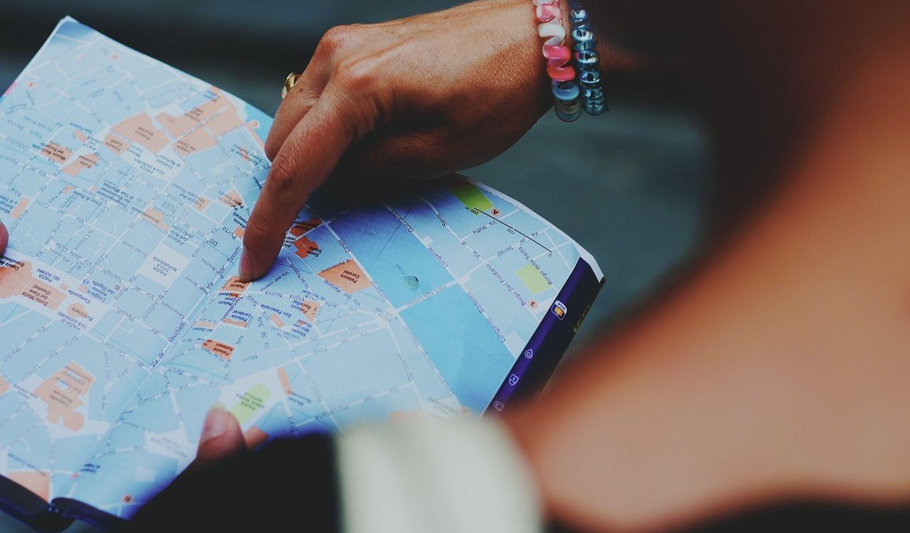 Person pointing at a paper map with city streets