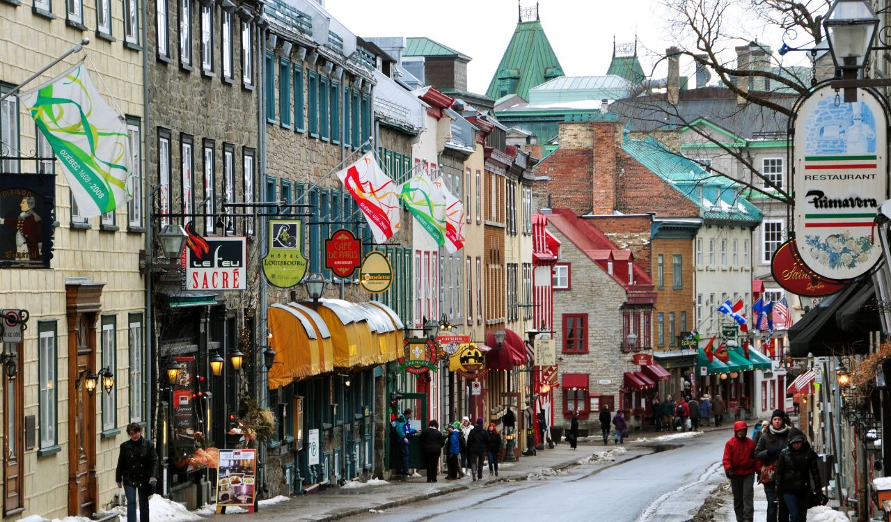 Old Quebec street with colorful buildings and people walking in winter.
