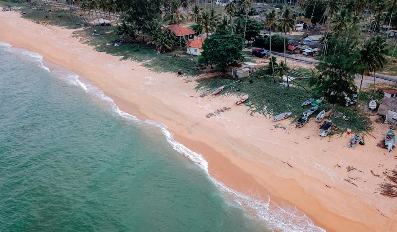 Aerial view of a tropical beach with boats and small homes along the shore