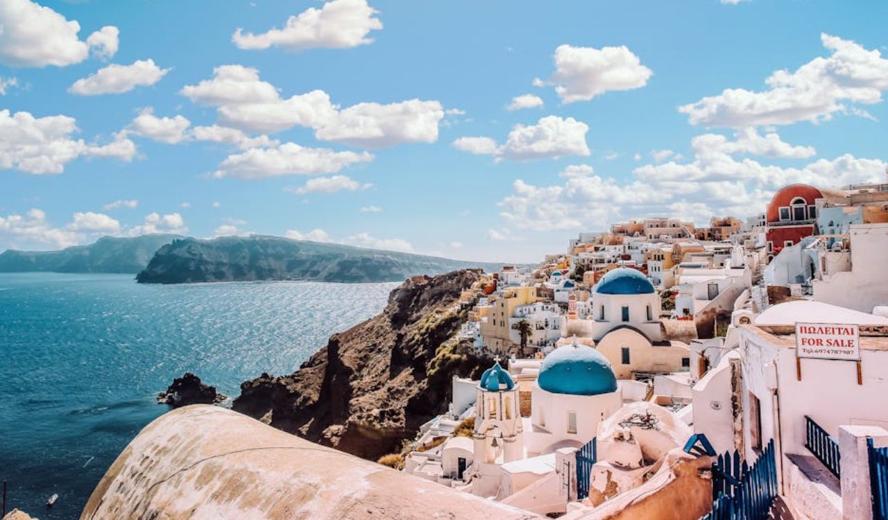 Blue-domed churches and whitewashed cliff houses overlooking the Aegean Sea in Oia, Santorini