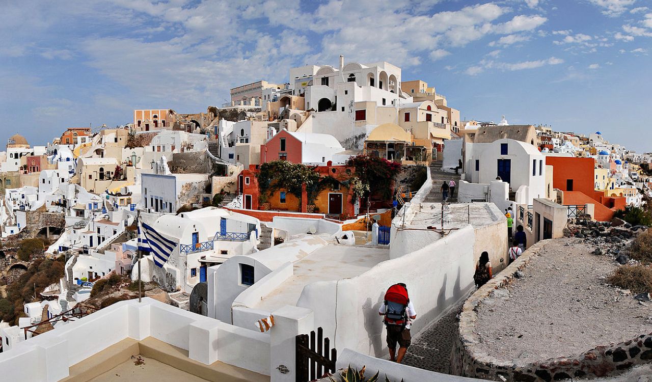 Colorful hillside houses in Santorini, Greece under a partly cloudy sky