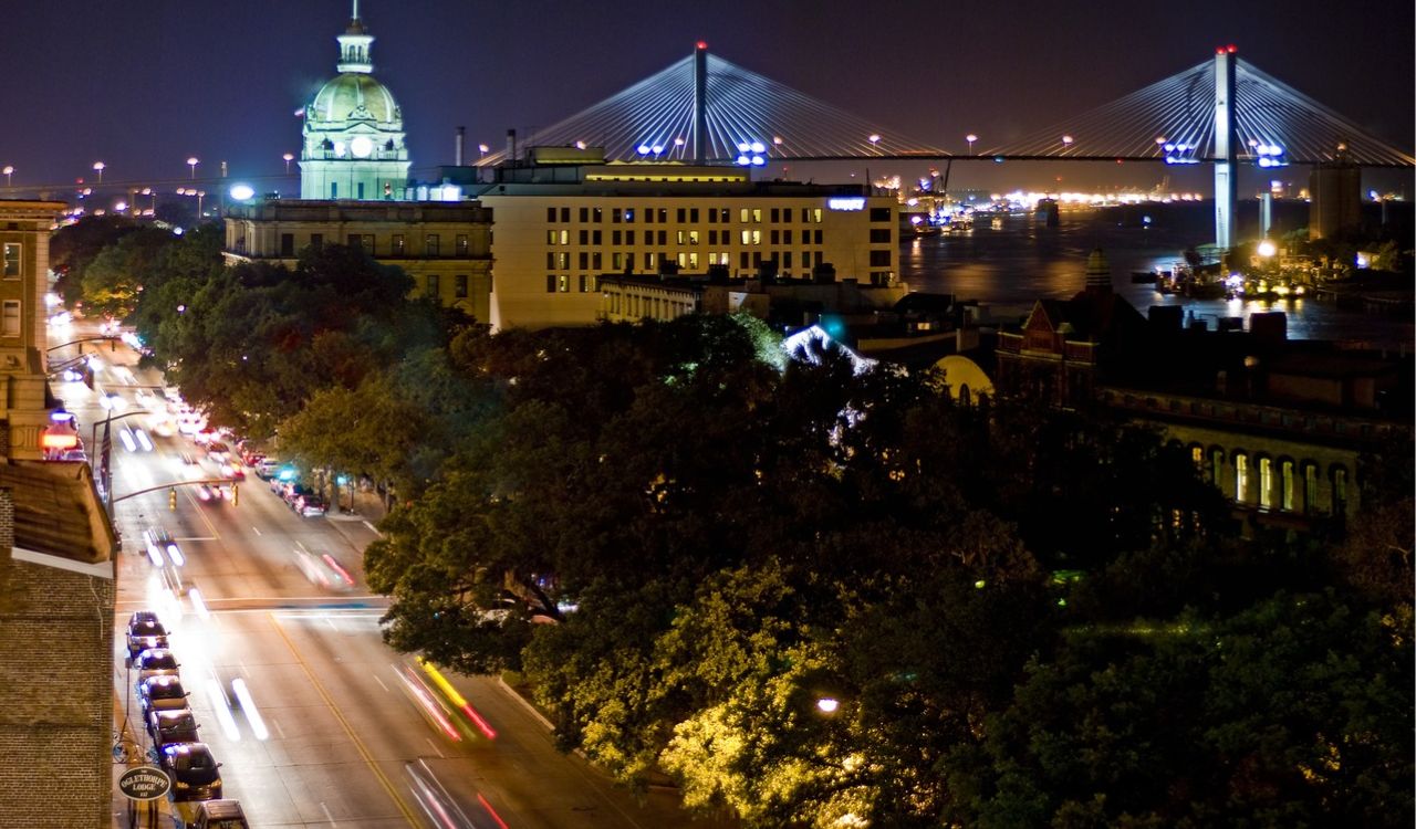 Night view of Savannah, Georgia with city lights and Talmadge Memorial Bridge in the background