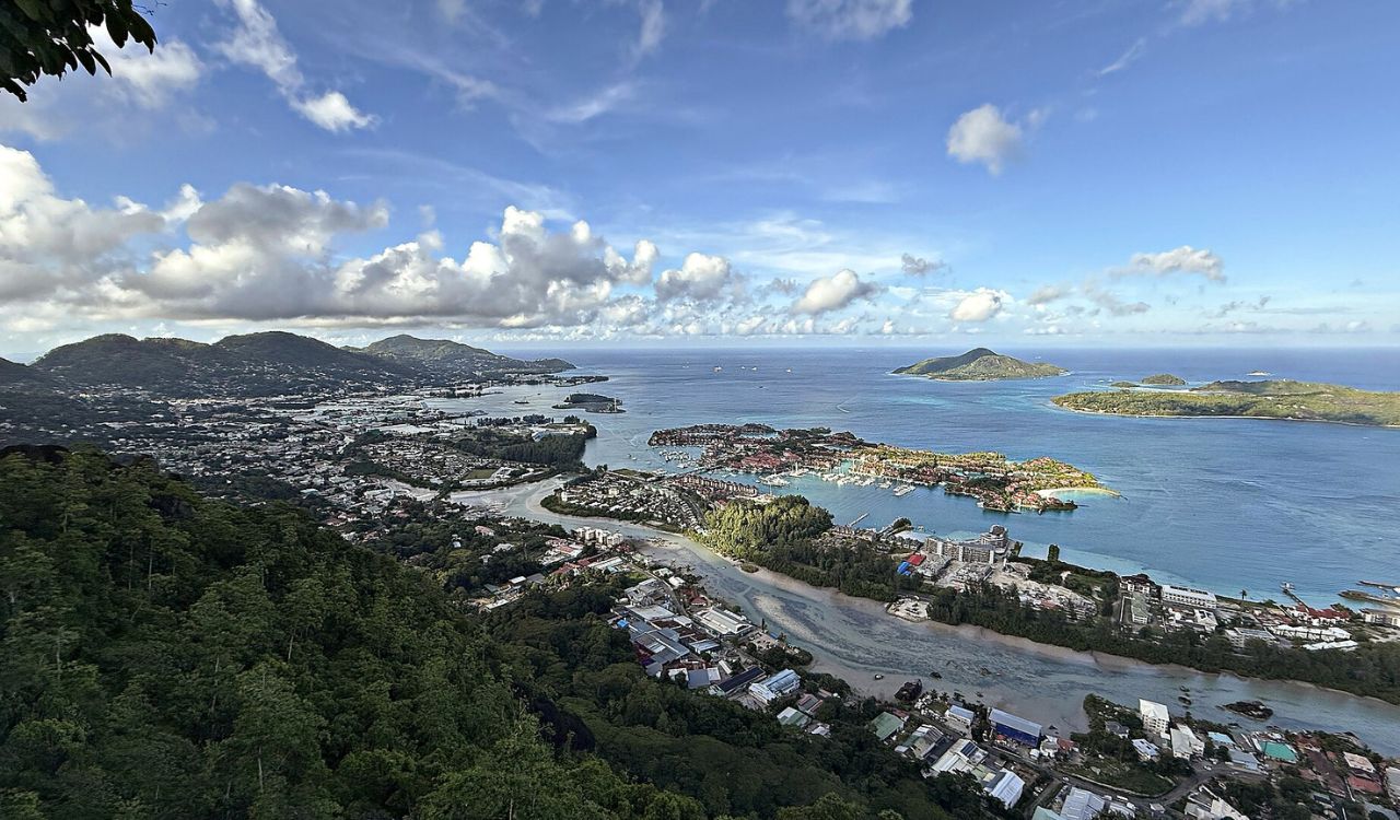 Panoramic view of Seychelles' lush hills and coastal city blending into turquoise island waters