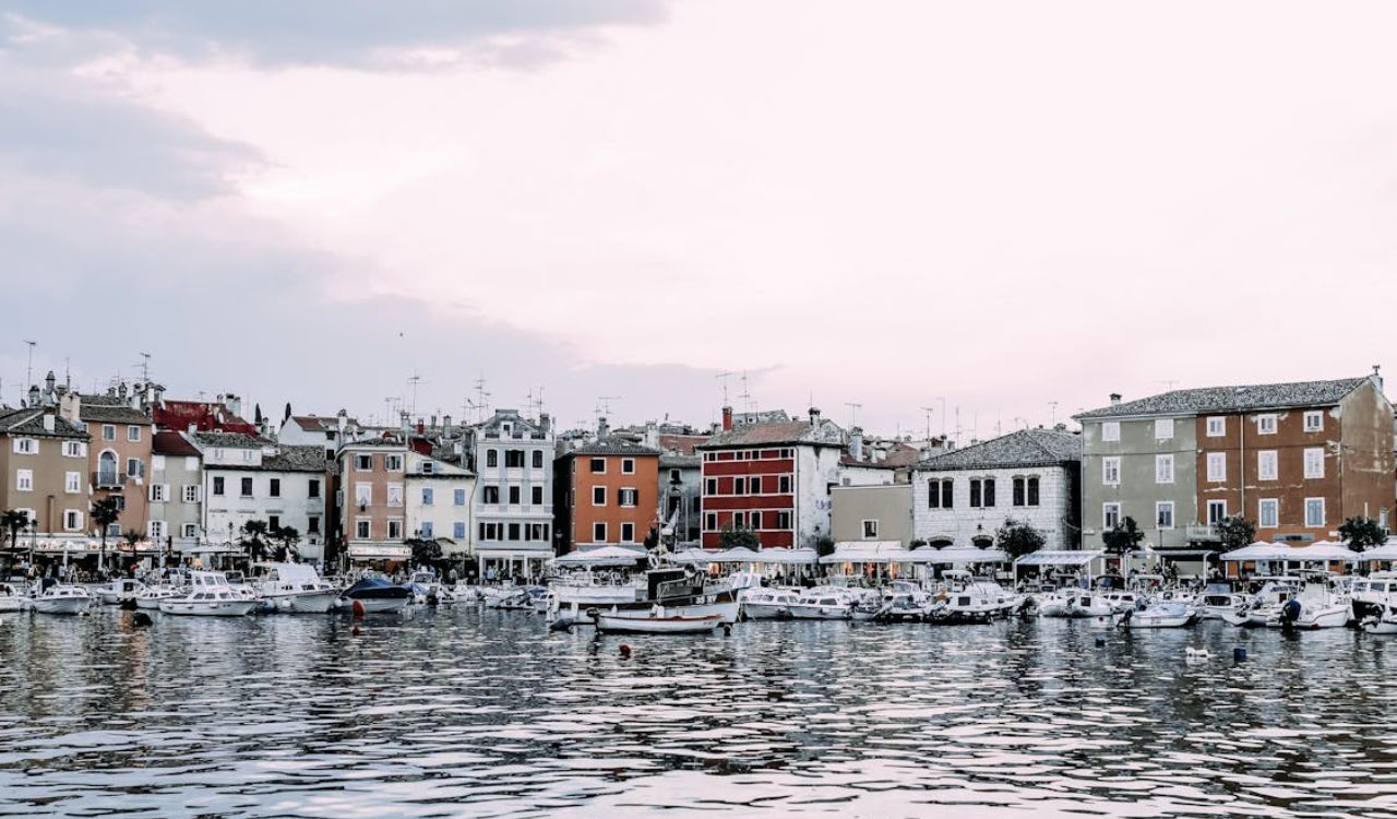 Colorful waterfront buildings and small boats lined up along the harbor in a quaint European town
