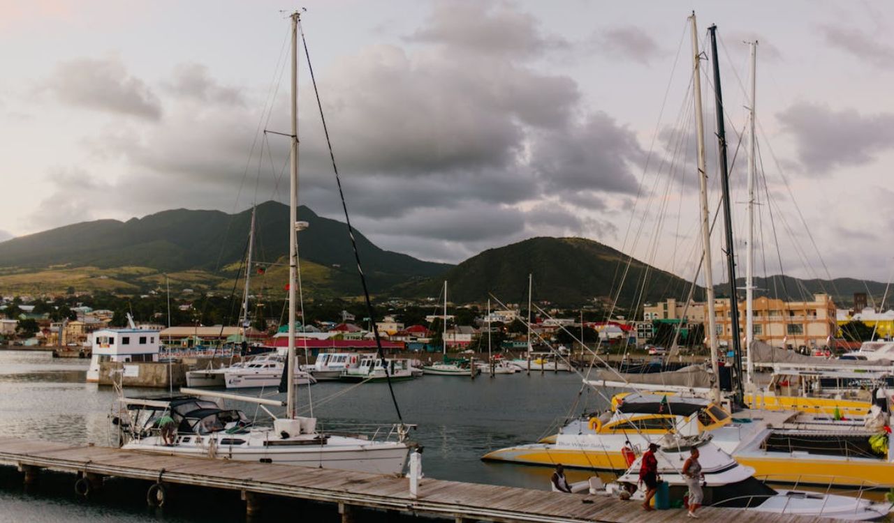 Colorful boats dock in a lively marina, backed by lush mountains in St. Kitts and Nevis