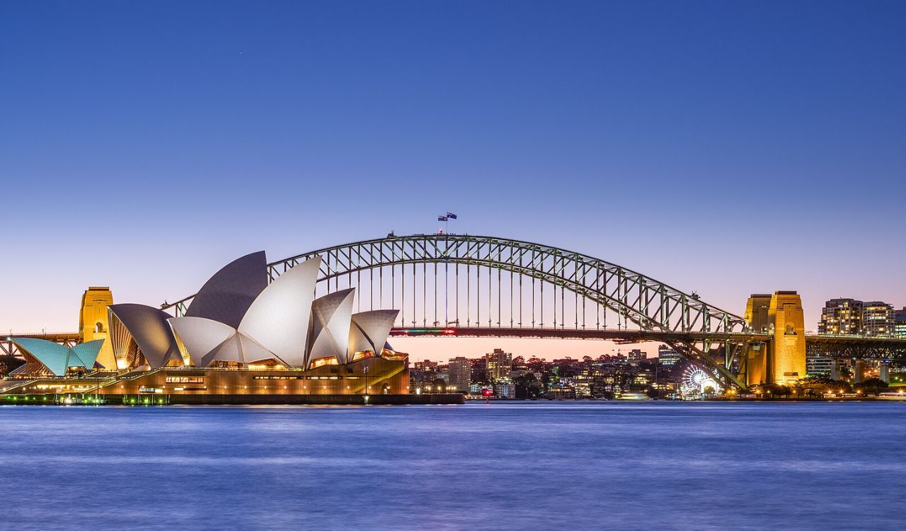Sydney Opera House and Harbour Bridge illuminated at twilight over the harbor.” Sources