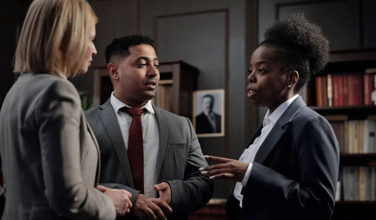 Three professionals in suits having a serious discussion in an office setting