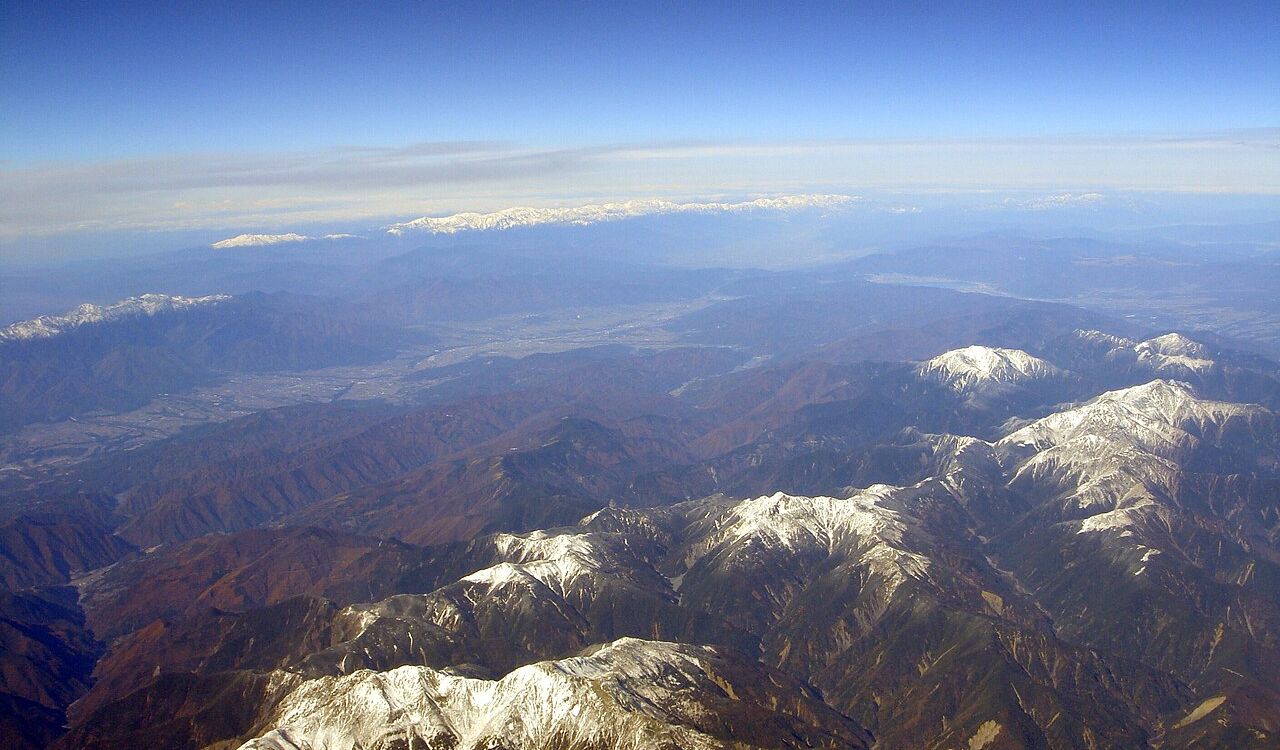 Aerial view of the snow-capped Japanese Alps with mountainous terrain and a clear sky