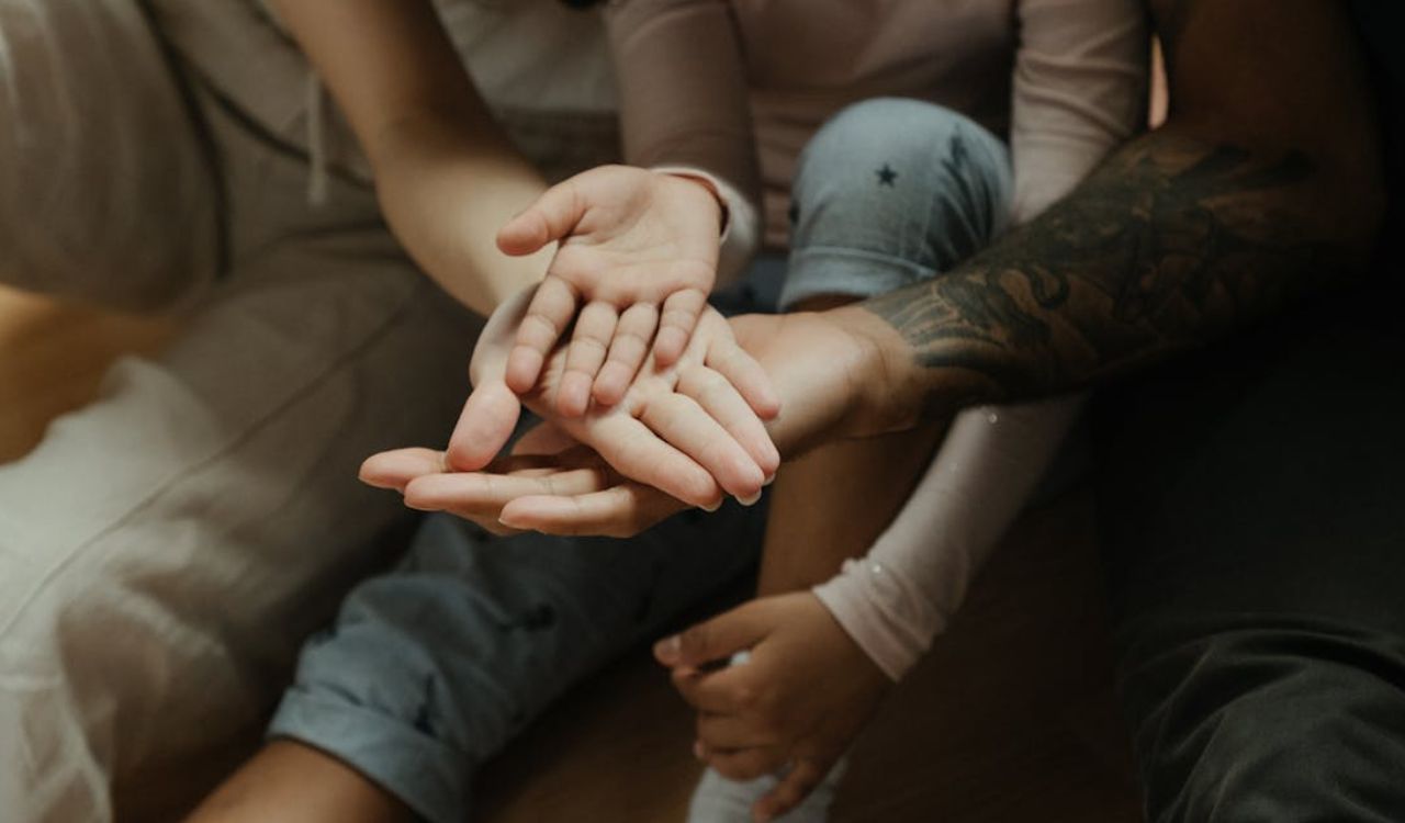 Close-up of a family’s hands stacked together, showing unity and care.