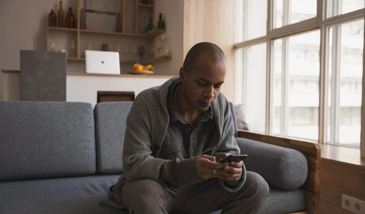 Man using a smartphone while house-sitting in a cozy modern apartment