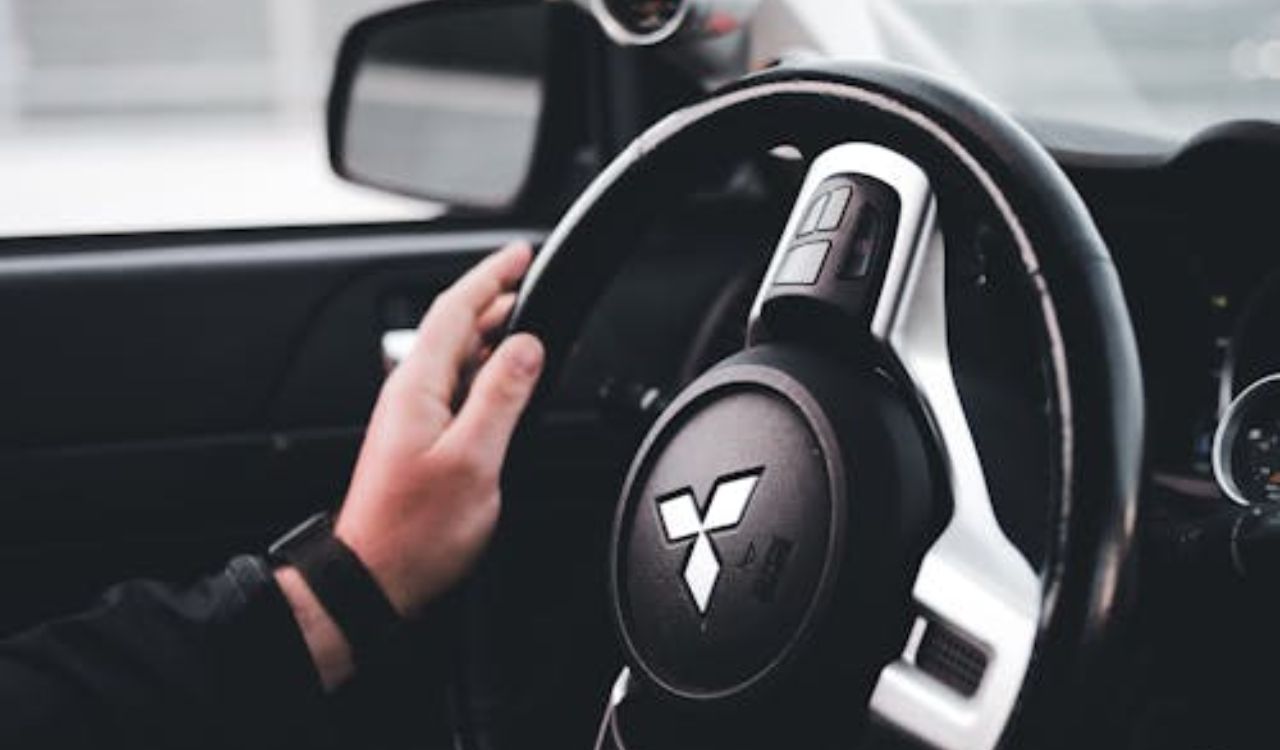Driver’s hand on a Mitsubishi steering wheel inside a modern car, suggesting cruise control usage for safer and more comfortable long-distance driving