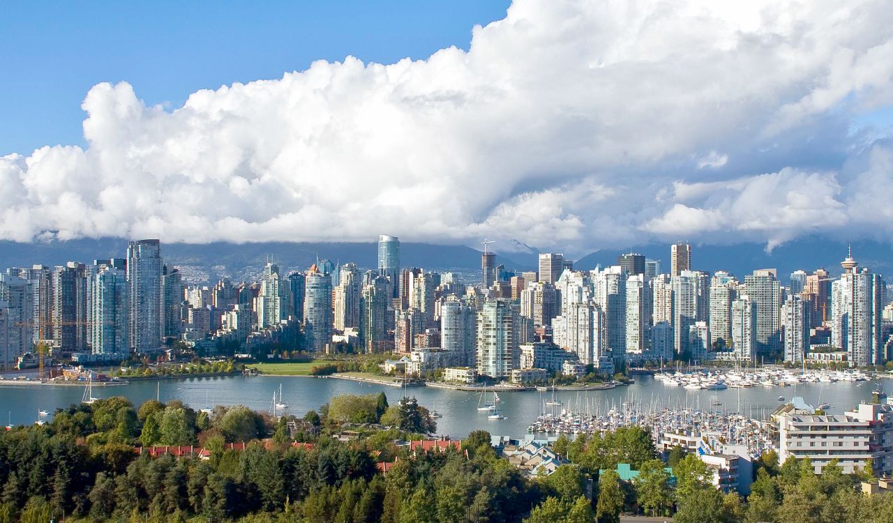Vancouver skyline with high-rises, marina, and mountains in the background.