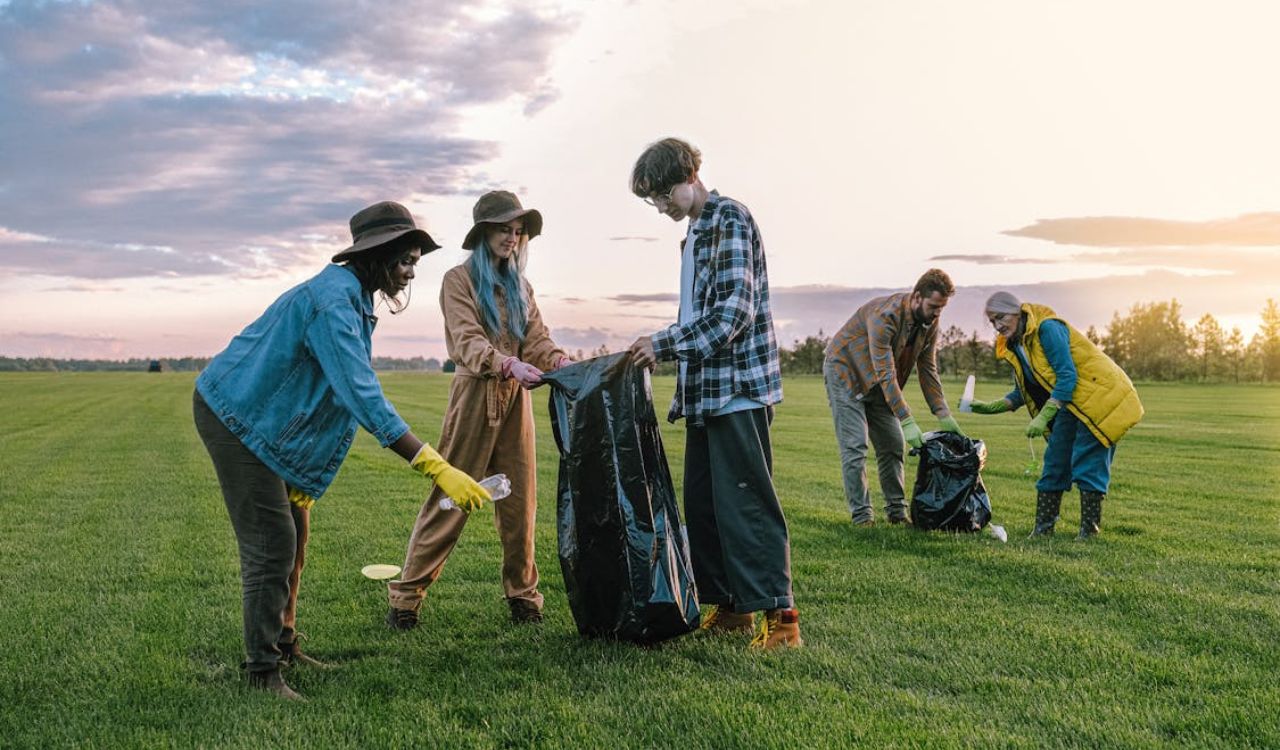 Group of volunteers cleaning up a park at sunset