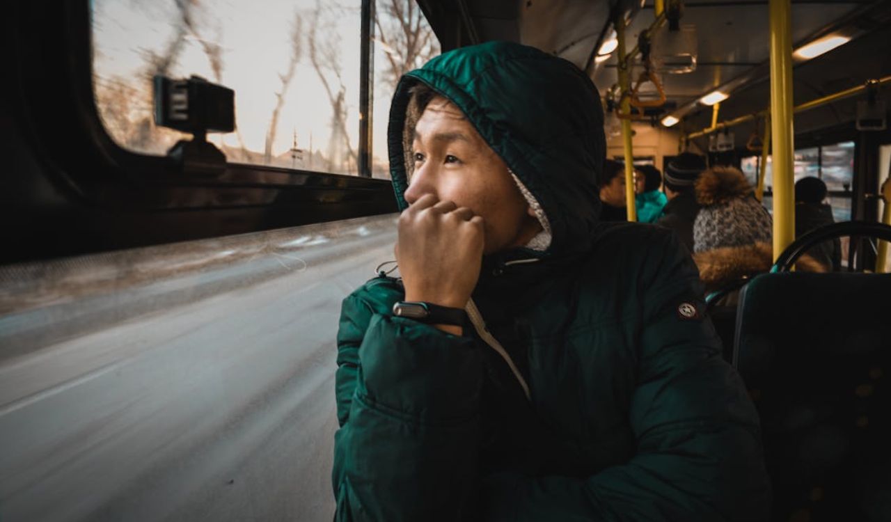 Man in a winter coat sitting on a bus, looking out the window