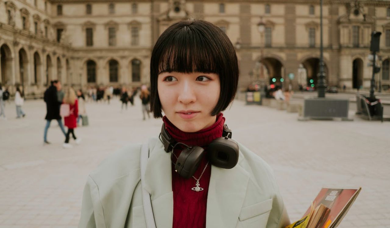 Person wearing headphones around their neck while standing in a busy public square