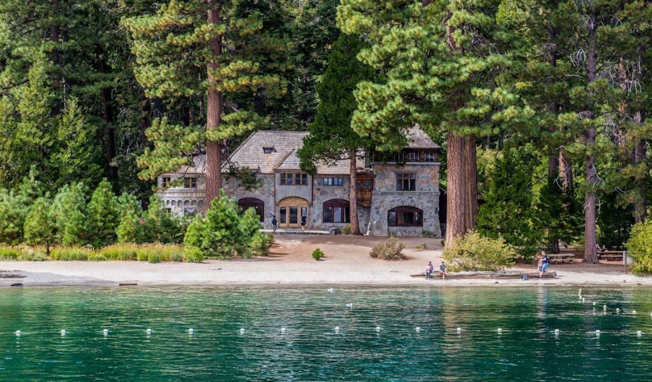 A charming stone cabin sits quietly among towering pines, right on the peaceful shores of Lake Tahoe